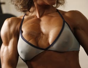 Female bodybuilder Erin poses in the gym, exposing her powerful legs, glutes, abs and pecs and flexing her muscular biceps. Erin is ripped and she’s stronger and sexier than ever – and that’s the truth. 