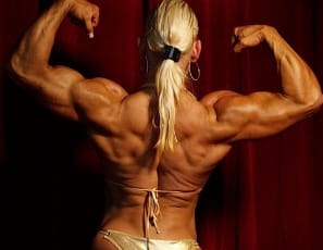 Professional bodybuilder Nicole Savage poses against red velvet curtains in a gleaming gold bikini, dazzling with the incredible musculature of her biceps and back, then getting nude so you can enjoy every muscular inch. All of Nicole is ripped, even her feet. 