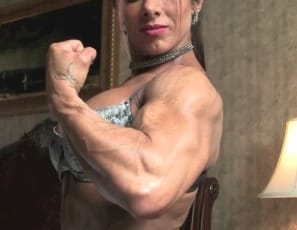 In sexy lingerie, stockings and high-heeled shoes, female bodybuilder Monica Martin is posing in the bedroom, showing you her muscle control of her powerful pecs, vascular biceps, her ripped abs, muscular legs and glutes, her tiny panties and her tattoo. Come closer, she says, stroking her calves. Ready?