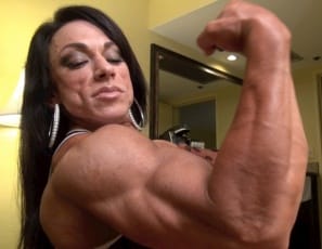 Wearing sky-high heels and a Naughty University top in the bedroom , tattooed female bodybuilder Carla poses to show you how vascular her big biceps are, how ripped her abs are, and how much control she has over the muscles of her pecs, legs, glutes and calves. Wonder what she could do to you? Naughty you!
